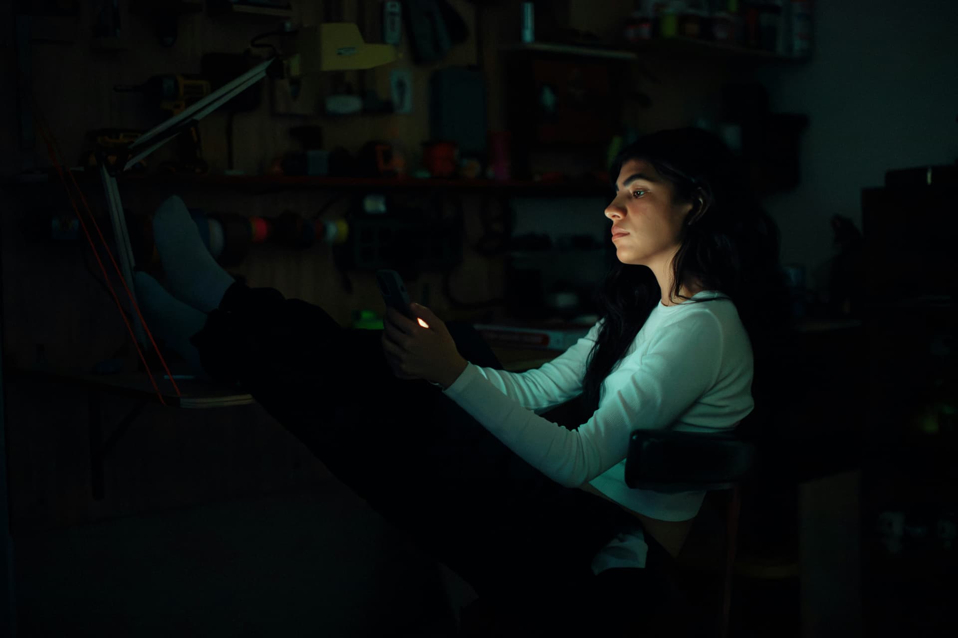 Person using a phone in a dark private workspace